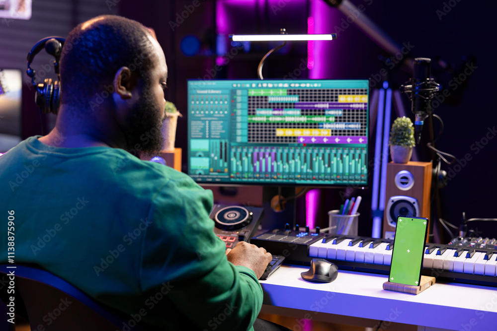 Poster songwriter working on making new music with a greenscreen on phone, operating on mixing console and 