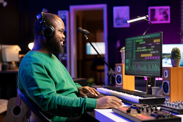 Music producer editing old audio recordings on professional software, operating on mixing console and stereo gear. Sound engineer producing new songs with acoustical tunes in home studio.