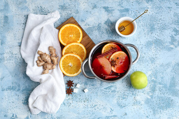 Cooking pot of hot mulled wine with apple, orange and different spices on blue background