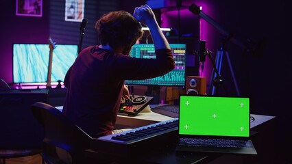 Musician mixing and mastering sounds at home studio with electronic console and soundboard, creating modern tunes. Sound engineer producing audio tracks with greenscreen on tablet. Camera B.