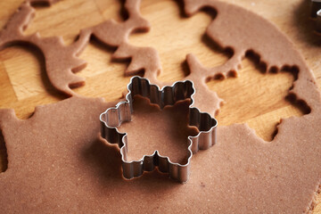 Fototapeta premium Cutting out star shapes from raw pastry dough - preparation of gingerbread Christmas cookies