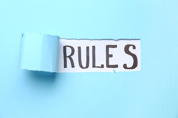 Word RULES visible through torn blue paper, top view