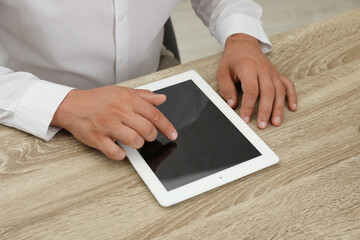 Businessman using tablet at wooden table, closeup. Modern technology