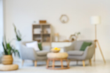 Obraz premium Blurred view of light living room with grey armchairs, table and shelf unit