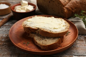 Fresh bread with butter on wooden table, closeup