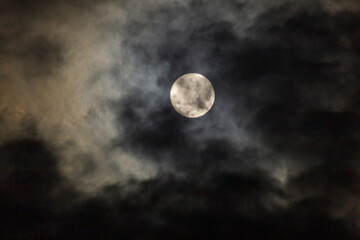 Full moon in the dark night sky with clouds, nature background.