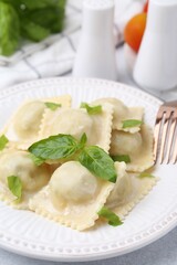 Delicious ravioli with cheese and basil served on light table, closeup