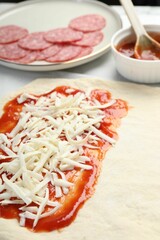 Making calzone pizza. Dough with sauce, cheese and other ingredients on table, closeup