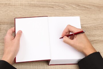 Obraz premium Writer signing autograph in book at wooden table indoors, above view