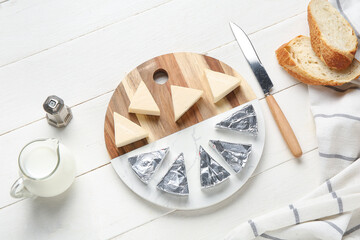 Composition with triangles of tasty processed cheese, bread, milk and knife on light wooden background
