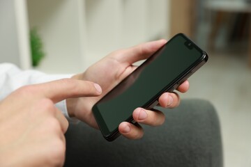 Man using smartphone with blank screen indoors, closeup