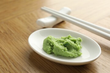 Hot wasabi paste and chopsticks on wooden table, closeup