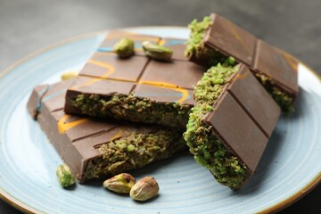 Pieces of Dubai chocolate bar with pistachios and knafeh on grey table, closeup