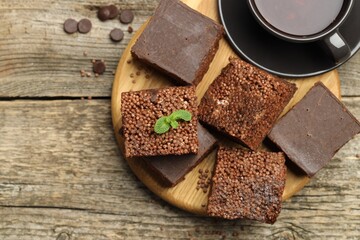 Delicious chocolate puffed rice bars and tea on wooden table, flat lay. Space for text