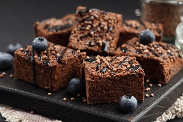 Delicious chocolate puffed rice bars and blueberries on gray table, closeup