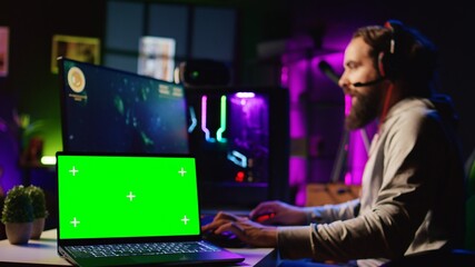 Chroma key laptop next to man playing high FPS singleplayer videogame with spaceship shooting...