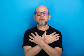 Bearded, bald man wearing prescription glasses and a black shirt with his arms crossed on his chest. Confident and focused
