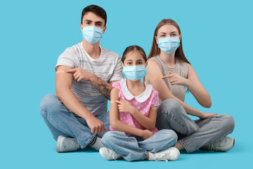 Family in masks pointing at medical patches after vaccination on blue background