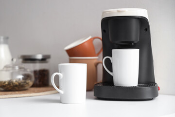 Coffee machine with cups on counter in kitchen, closeup