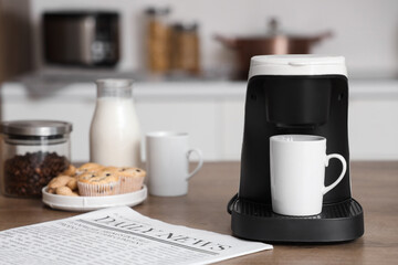 Coffee machine with cup on table in kitchen, closeup