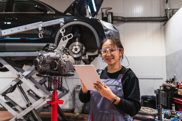 Young chinese female mechanic using digital tablet in auto repair shop