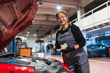 Female chinese mechanic checking oil level of car in repair shop