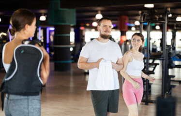 Guy and girl leave gym, after completing classes they go to exit of room. Visitors of sports club come out after training