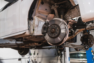 Car disk brake getting fixed on elevated vehicle in auto repair shop