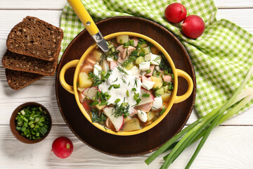 Composition with bowl of tasty okroshka, ingredients and bread on light wooden background