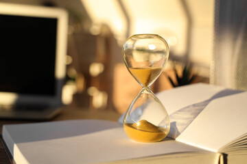 Hourglass on book in office, closeup