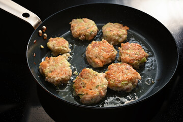 Fish cakes or frikadelles from salmon are roasted in a black frying pan, cooking for dinner or...