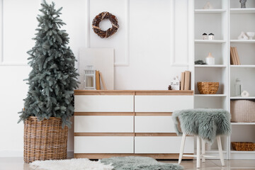 Interior of living room with Christmas tree, commode and shelf unit