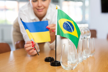 Little flag of Brazil on table with bottles of water and flag of Ukraine put next to it by positive...