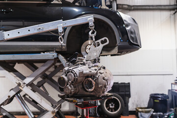Fototapeta premium Engine crane lifting gearbox in auto repair shop