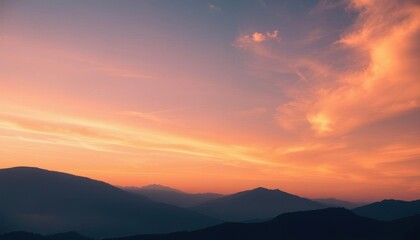 Fototapeta premium mountains are silhouetted against a sunset sky with a pink and orange sky