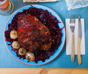 Top view of crispy beer roasted whole pork knuckle served with braised cabbage and onion