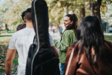 A group of friends enjoys a sunny day in the park, walking together with a guitar. The atmosphere...