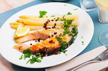 Traditional spanish food, grilled salmon with asparagus served with lemon and greens