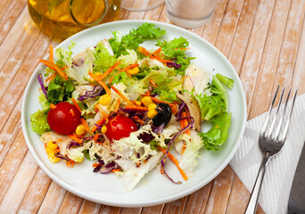 Fresh mixed salad with lettuce, corn, olives and cherry tomatoes at plate
