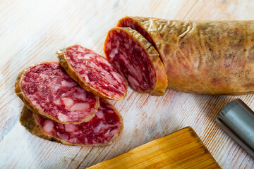 Spanish salchichon sausage cut in slices on a wooden surface, close-up