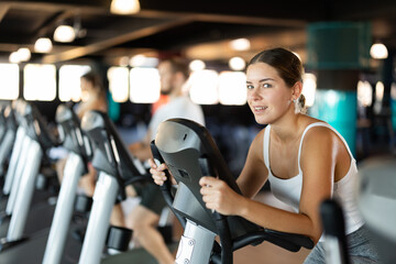 Young athletic woman working out on exercise bike in gym