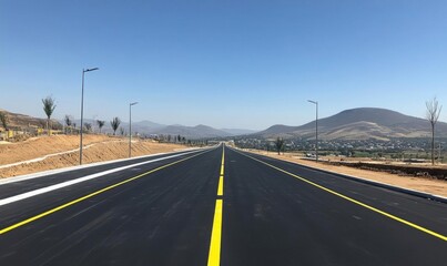 A newly paved road stretches into the distance under a clear sky.