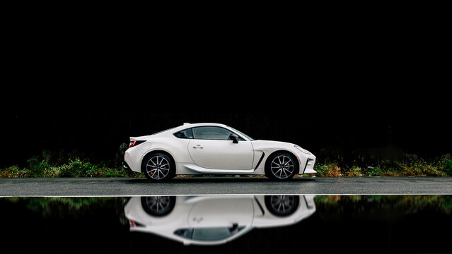 Minato, Tokyo, Japan - November 22 2024: A White Toyota Gazoo Racing GR86 sports coupe is parked in front of a black wall on cloudy and wet rainy day with mirrored reflection