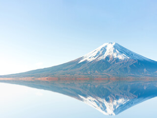 A mirrored reflection of snow capped Mount Fuji on a cold and sunny autumn winter morning with clear blue sky, no clouds or people and copy space. cool temperature and isolated image with mist
