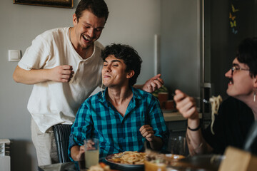 A group of friends sharing a fun and lighthearted moment during dinner, enjoying delicious pasta and laughter. The mood is warm and friendly, highlighting companionship and good times.