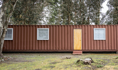 Minimalistic shipping container house home, tiny house in sunny day. Shipping container houses is sustainable, eco-friendly living accommodation or holiday home