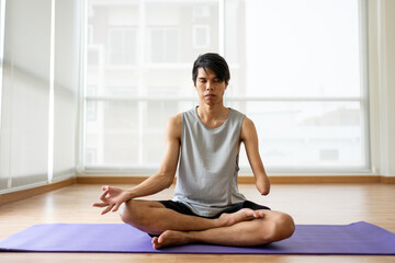 Asian young amputee male without arm doing yoga in the fitness gym. 