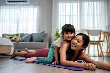 Obraz premium Portrait of Asian mother and daughter doing workout together in house. 