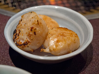 Three grilled scallops in ceramic bowl close-up