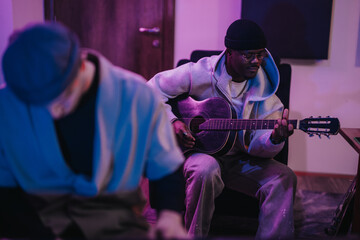 Obraz premium Two musicians of diverse backgrounds collaborate in a recording studio, creating beautiful music together. The warm, inviting atmosphere enhances their creative synergy and musical performance.